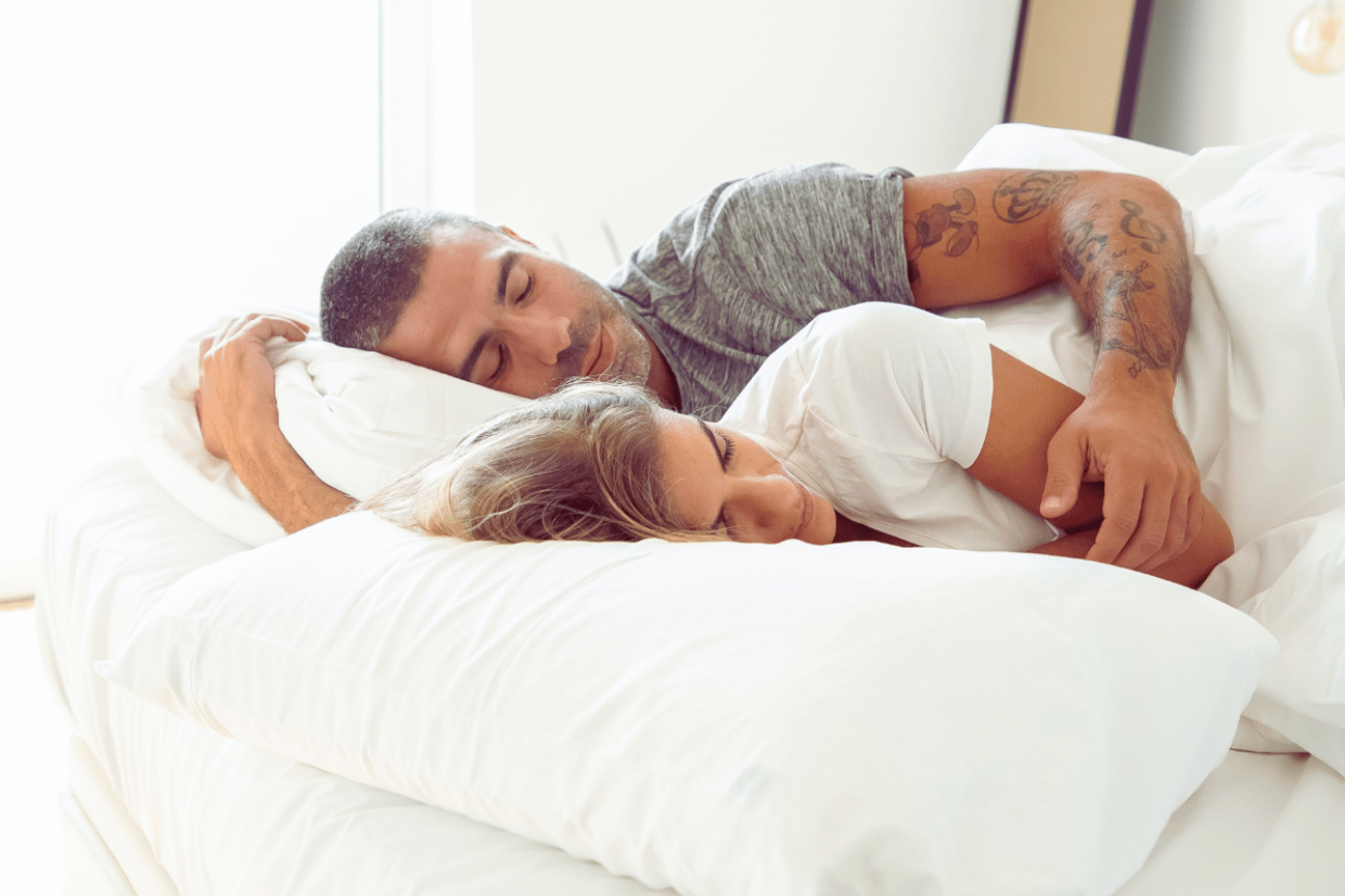 man and woman sleeping side by side in an all white linen bed