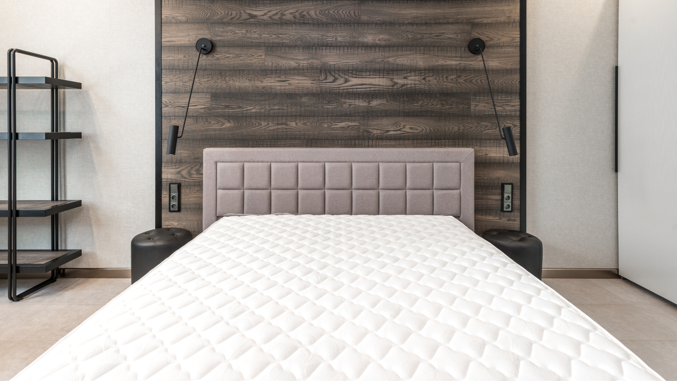 Bedroom with a large uncovered mattress on contemporary bed frame.