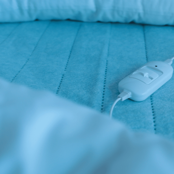 closeup of a light blue heated blanket on a bed and its white controller