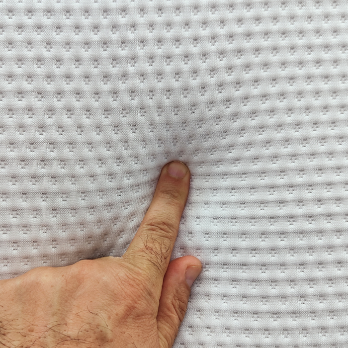 Index finger of a man’s hand pressing down on a mattress. 