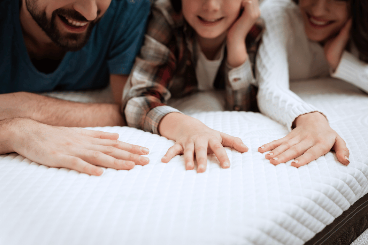 Couple with their child all touching a mattress to feel its material