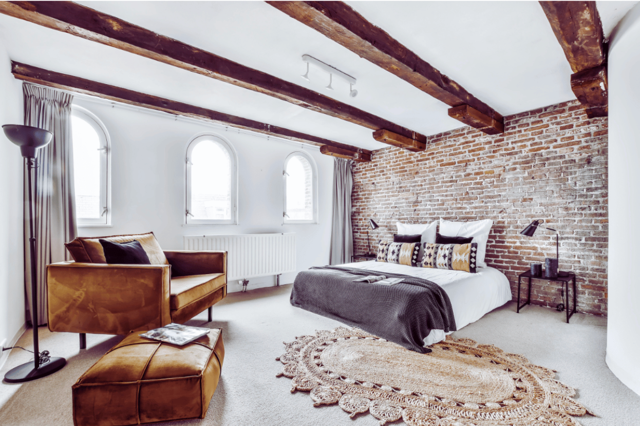 furnished bedroom with an exposed brick wall and wooden beams