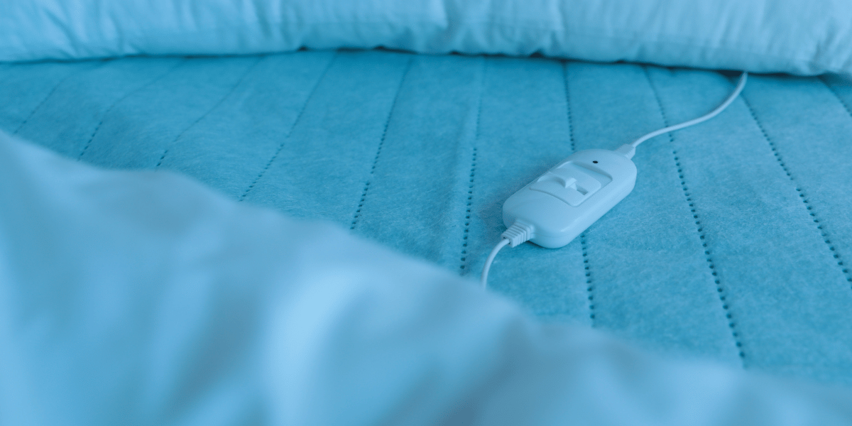 closeup of a light blue heated blanket on a bed and its white controller