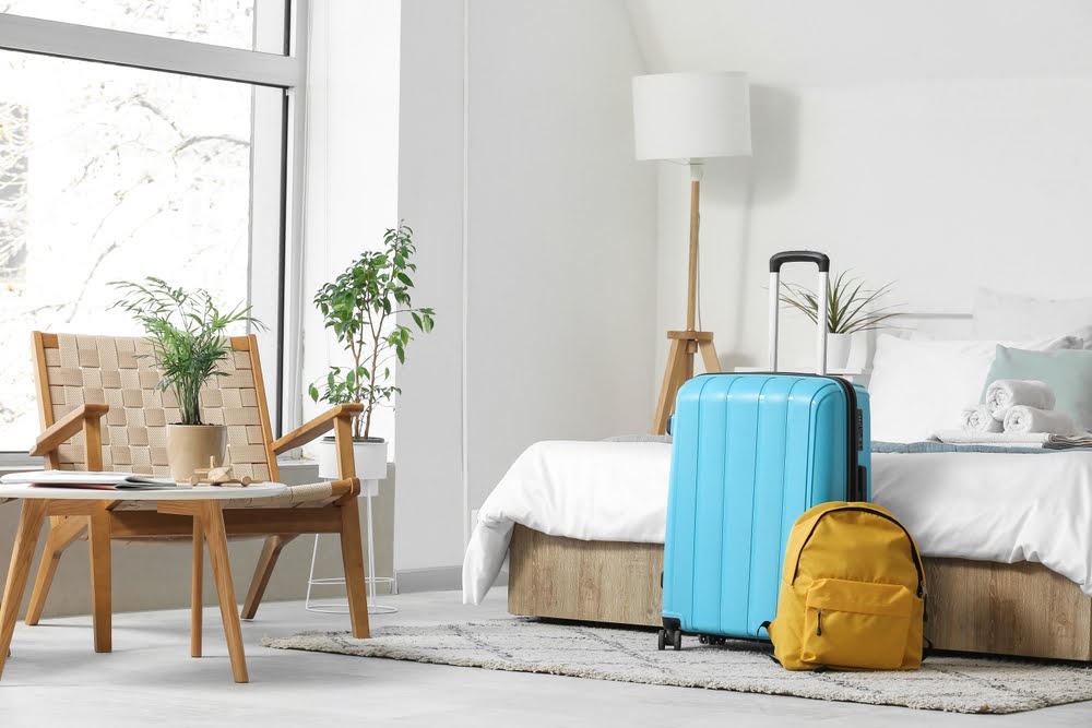 guest bedroom with a piece of luggage and backpack on the floor at the foot of the bed