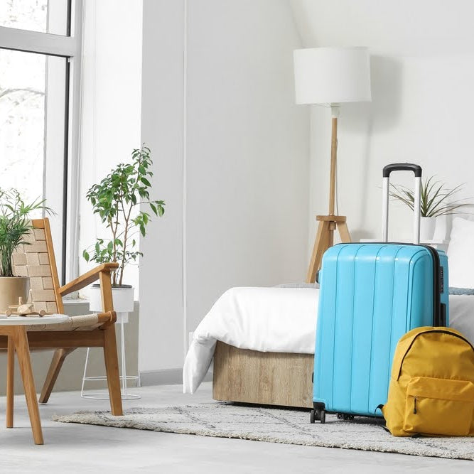 guest bedroom with a piece of luggage and backpack on the floor at the foot of the bed