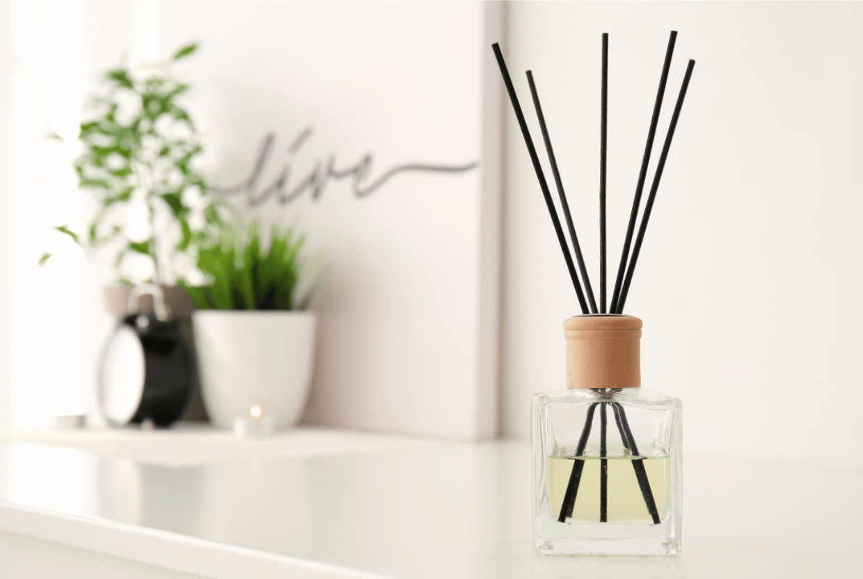 reed scent diffuser on a white countertop near an alarm clock
